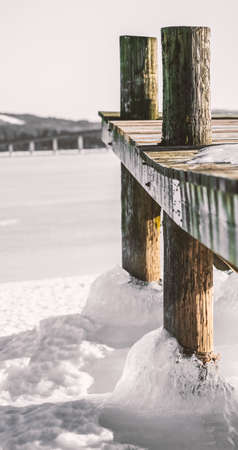 Old worn wooden pier locked on thick sea ice on a clear cold winters day. Shallow depth of field. High quality photoの写真素材