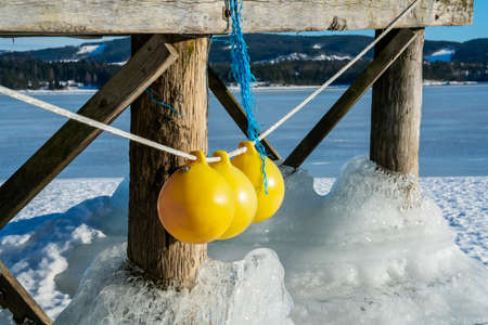 Thick ice clinging to the wooden pillars of a boat jetty on a frozen lake. High quality photo