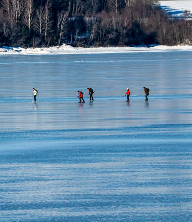 Group of people skating on the clear ice on a frozen sea. High quality photoのeditorial素材
