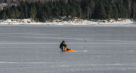 Angler fishing on the ice of a frozen lake on a clear winters day. High quality photoのeditorial素材