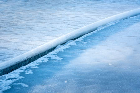 Large clean crack in sea ice with white snow on the top and clear blue ice beneath. Close up. High...