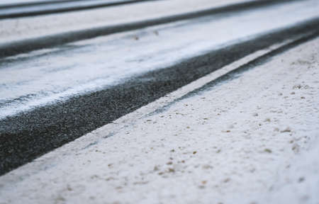 Close up of an asphalt road covered in snow and ice. Shallow depth of field. High quality photo