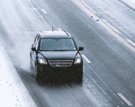 Car driving on a highway with wet slippery asphalt during a snow storm. . High quality photoの写真素材