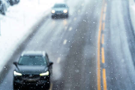 Blurred out image of cars driving on a highway with wet slippery asphalt during a snow storm. . High quality photoの写真素材