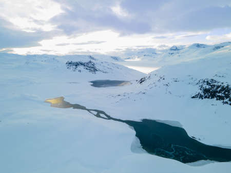 Stunning aerial view of a river flowing through a snow covered tundra and mountain range. High quality photoの写真素材