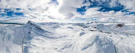 Spectacular panoramic view over snowcapped mountain peaks, ridges and frozen highland tundra in...