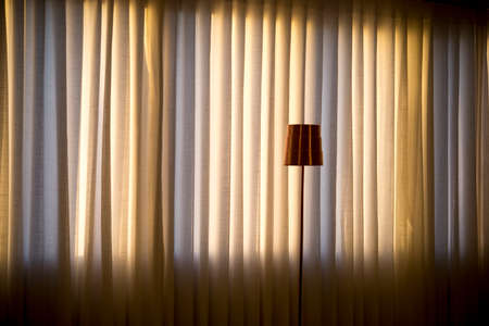 very smooth blue and yellow curtain background with small copper bedside lamp.の写真素材