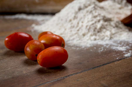 cherry tomatoes and flour on the wooden table with Free space for textの写真素材