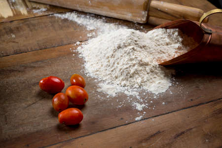 cherry tomatoes, rolling pin and flour on the wooden table with Free space for text, top view, copy space.の写真素材