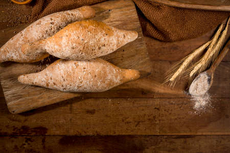 sliced whole grain bread,baguettes on rustic wood with whole flour pot in the background.