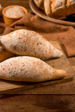 sliced whole grain bread,baguettes on rustic wood with whole flour pot in the background.