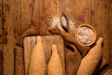 whole grain bread,baguettes on rustic wood with whole flour pot in the background.top view,...