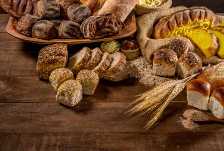 several breads made with sesame seeds, sunflower seeds,  corn meal, linsced, oatmeal, barley, rye, chia, pumpkin seed, poppy, nutmeg, on rustic wooden table, letteringの写真素材