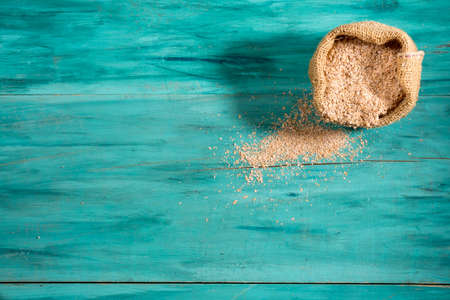 small bag with whole wheat flour on textured blue wood space for text, top viewの写真素材