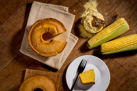 corn cake witout slice on rustic wood and fabric with corn, slice in plate and cake in background...