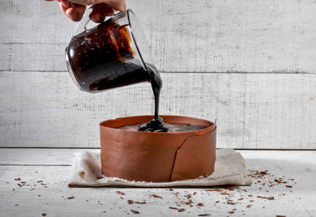 chocolate cake over white rustic wood with pouring syrup bowl.の写真素材