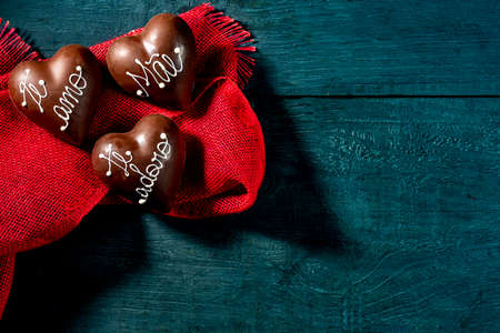 chocolate hearts with writing in Portuguese  ââ te amo, te adoro, mÃ£eââ, on red fabric. top view, space for text.の写真素材