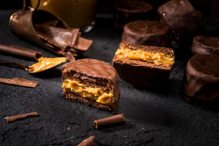 cookies alfajores with cream dulce de leche close-up on the black stone, vanilla macaroons covered with chocolateの写真素材