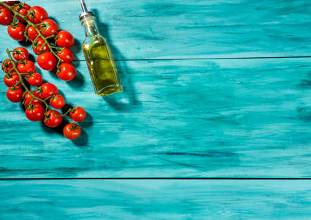 cherry tomatoes and bottle of olive oil on blue wood top view. with space for textの写真素材
