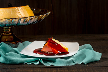 close up of a sweet syrup pouring over caramel custard pudding on a glass cake standの写真素材