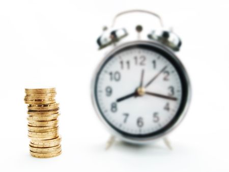 Pile of coins and alarm clock on a white backgroundの写真素材