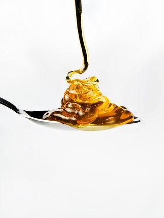Honey on a spoon over a white backgroundの写真素材