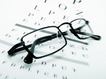 Eye glasses on an optometrist chart の写真素材