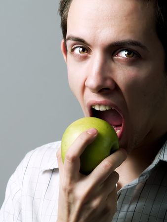 Young man eating a green appleの写真素材