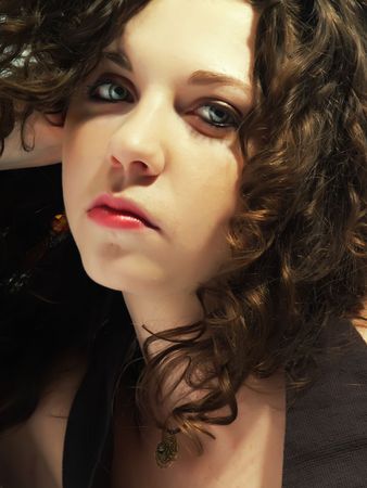 A portrait about a pretty lady with white skin and long brown wavy hair who wears a nice dark dress and she is thinkingの写真素材
