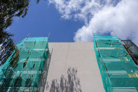 Building under construction with scaffolds against blue skyのeditorial素材