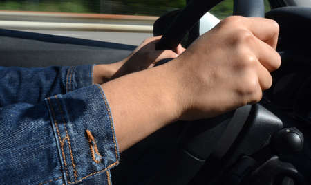 Right hand holding the wheel while driving on roadの写真素材
