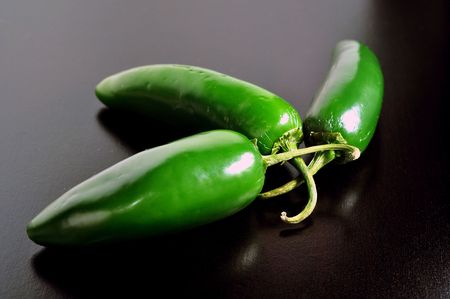Three jalapeños on a black tableの写真素材