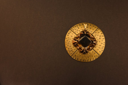 A gold pendant with a large ruby gemstone on a brass circle.の写真素材