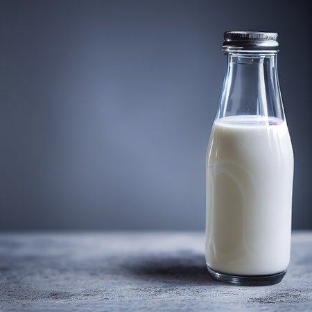 Small glass milk bottle with cap on a table. Close up studio shot, isolated on gray background.の写真素材