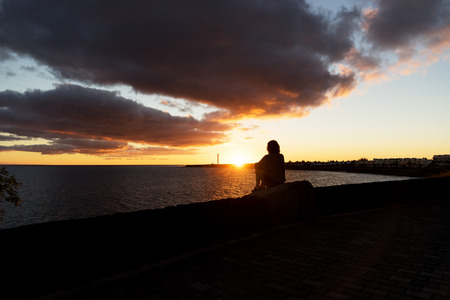 Sunset in Playa Blanca as seen from the Boulevard with the lighthouse Pechiguera in the distance.の写真素材