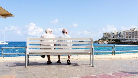 Two people sitting on a bench in Marsalforn harborのeditorial素材