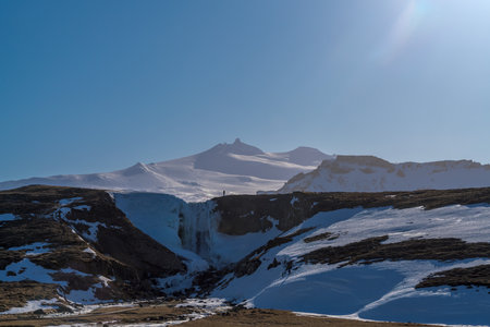 Frozen Svodufoss waterfall just after sunrise in the Snaefellsnes peninsula in Iceland with the SnÃ¦fellsjÃ¶kull glacier/volcano in the backgroundの写真素材