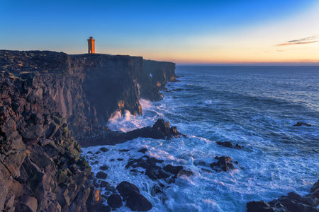 Svortuloft, spelled SvÃ¶rtuloft in Icelandic, is a 4 kilometer long pitch-black coastal cliff with a bright orange lighthouse situated at the western tip of the Snaefellsnes Peninsula in West Iceland.の写真素材