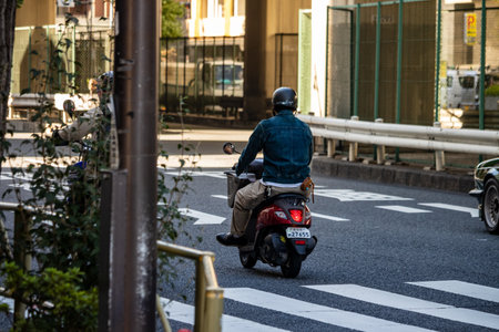 Tokyo, Japan, October 26, 2023: Motorcyclist Riding on an Urban Road at Duskのeditorial素材