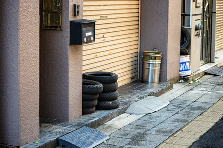 Tokyo, Japan, October 26, 2023: Stacked Tires and Trash Can by a Residential Buildingのeditorial素材