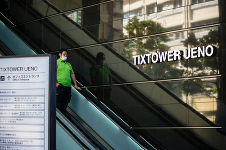 Tokyo, Japan, October 26, 2023: Man descending on an escalator near TIXTOWER UENO signのeditorial素材