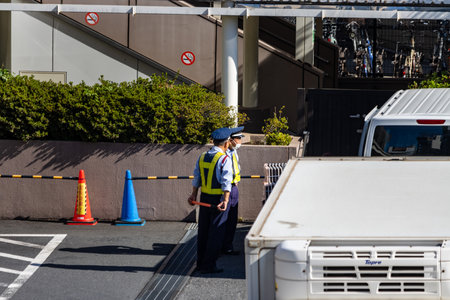 Tokyo, Japan, October 26, 2023: Security Officer Directing Traffic Near Construction Siteのeditorial素材
