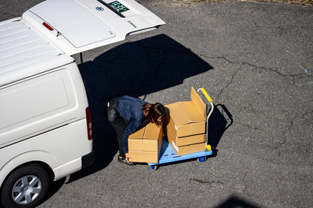 Tokyo, Japan, October 26, 2023: Delivery Worker Transporting Packages with a Hand Truck