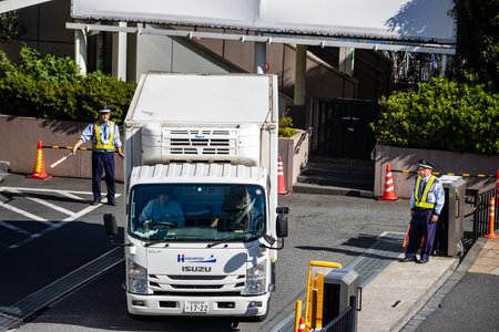 Tokyo, Japan, October 26, 2023: Security Guard Directing Traffic at a Truck Entrance
