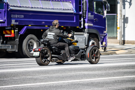 Tokyo, Japan, October 26, 2023: Motorcyclist riding a three-wheeled bike on a busy Tokyo street.