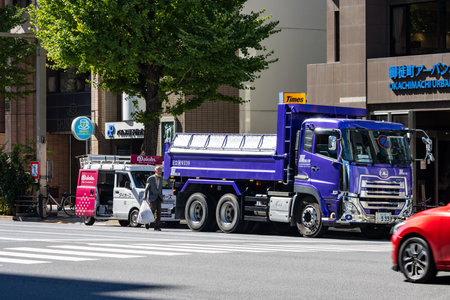 Tokyo, Japan, October 26, 2023: Construction truck in motion on city road with commercial buildings.のeditorial素材