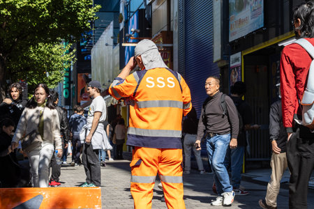 Tokyo, Japan, October 26, 2023: Construction worker overseeing safety in a busy Tokyo streetのeditorial素材
