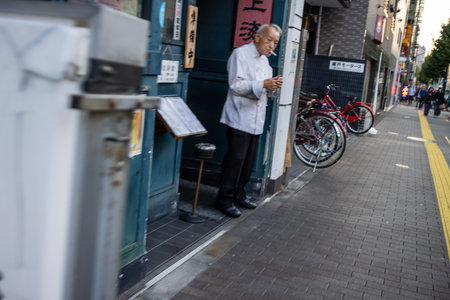 Tokyo, Japan, October 28, 2023: Chef reading outside his restaurantのeditorial素材