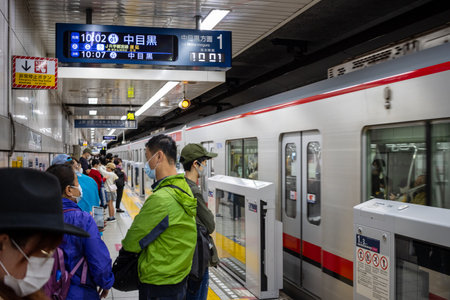 Tokyo, Japan, October 29, 2023: Subway train arriving at station with passengers waitingのeditorial素材