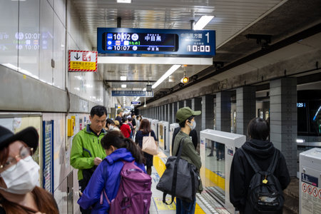 Tokyo, Japan, October 29, 2023: Commuters in subway station with digital timetableのeditorial素材